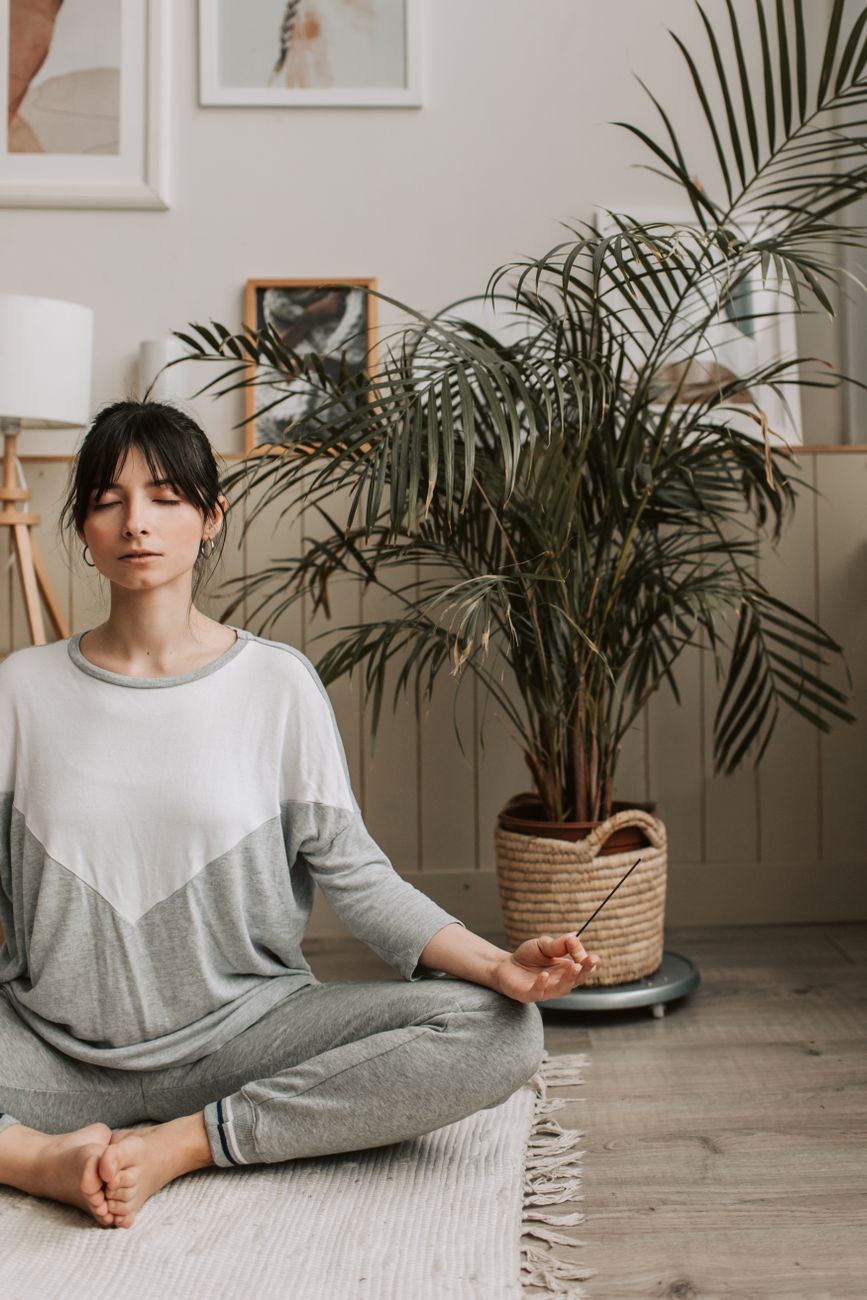 Woman sitting in a meditation pose, eyes closed, in a quiet room